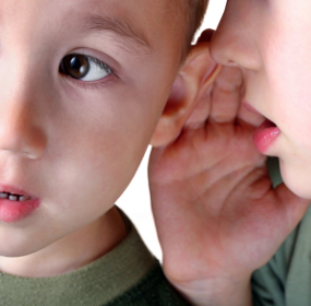 Маленький мальчик шепчет на ухо младшему брату